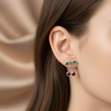 Load image into Gallery viewer, A pair of silver-toned earrings on a textured light green. One earring features cherrie design, with a post and butterfly clasp.
