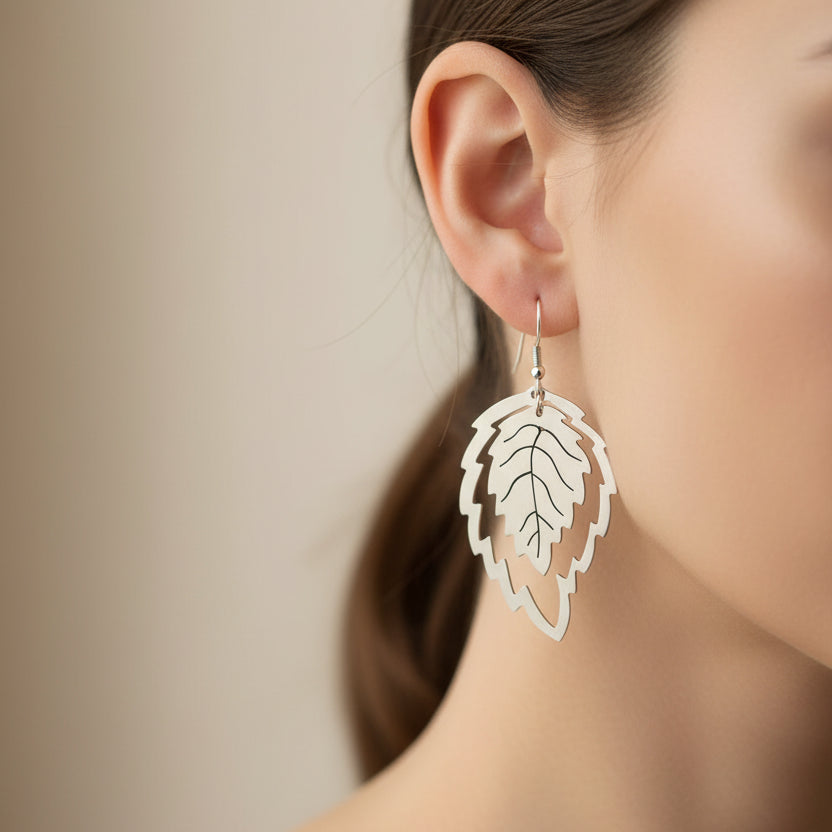 Silver leaf-shaped Hojas earrings on a clean white background
